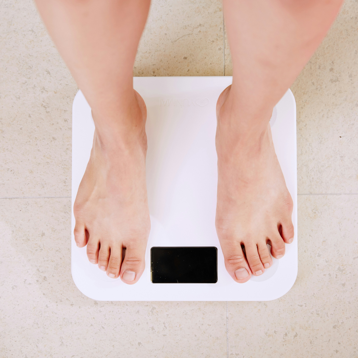 An individual standing on a scale to weigh themselves.